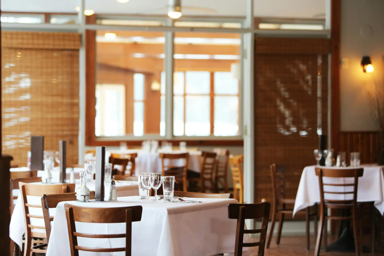Salle de restaurant lumineuse avec des tables dressées de nappes blanches