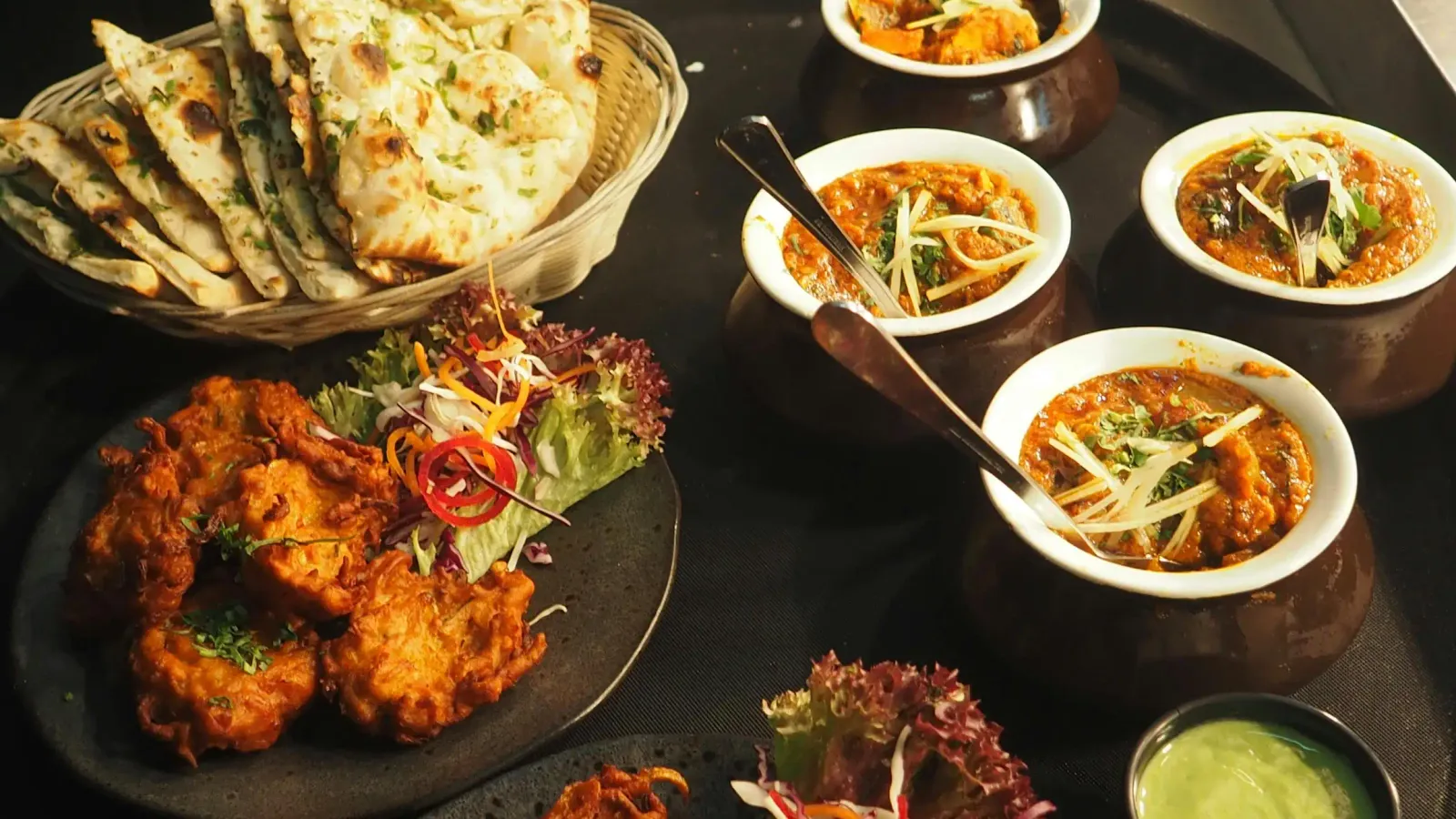 Table garnie de plats indiens, currys, naans et beignets